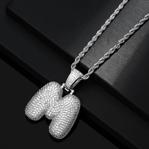Detailed macro view of silver bubble letter M pendant with iced out pavé zircon stones