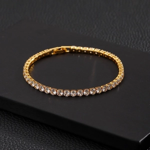 Macro view of gold tennis bracelet featuring round cubic zirconia and folding clasp