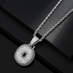 Macro shot of silver hip hop pendant encrusted with white zircon stones on rope chain