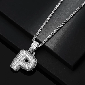 Macro shot of iced out silver letter P pendant with sparkling zircons and twist chain