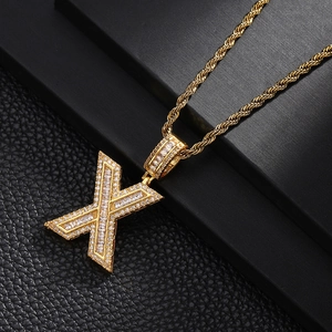 Detailed macro view of gold-plated letter X pendant with sparkling cubic zirconia inlay