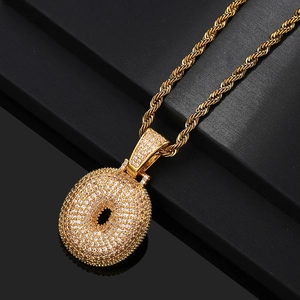 Detailed close-up of a gold donut pendant with sparkling pavé zircons on a rope chain