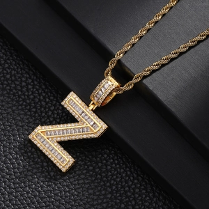 Close-up of iced out letter N pendant with pavé cubic zirconia on golden rope chain