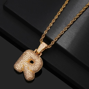 Macro detail of gold-plated bubble letter R pendant with sparkling zircon inlay