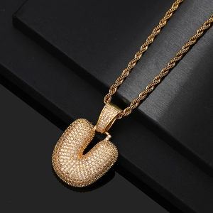 Macro detail of gold-plated bubble letter U pendant with iced out cubic zirconia stones
