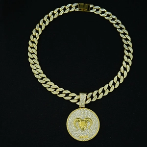 Macro detail of gold Cuban link chain with iced out Aries ram pendant and white crystals