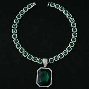 Detail shot of luxury Cuban chain featuring emerald green stones and white pavé crystals