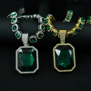Detailed macro of gold and silver cuban necklaces with emerald cut green gemstones
