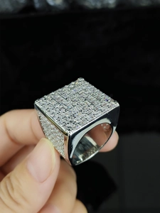 Dettaglio macro di un anello hip-hop da uomo squadrato in argento con pavé di zirconi