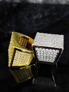 Dettaglio macro di anelli quadrati hip hop con finiture oro e argento e pavé di zirconia