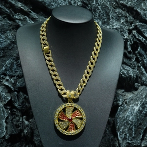 Detalle del colgante giratorio hip-hop dorado con circonitas rojas y blancas en cadena cubana