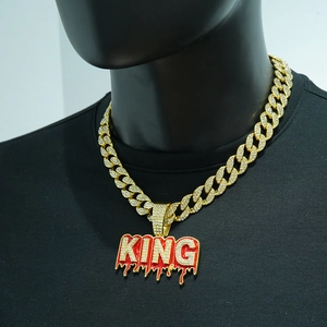 Dettaglio catena cubana dorata con ciondolo KING di diamanti e smalto rosso su maglia nera