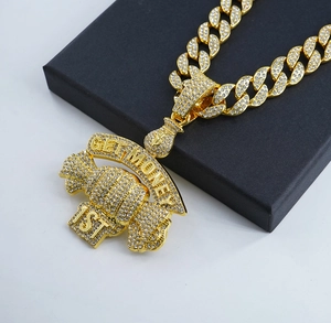 Macro detail of iced-out GET MONEY 1ST money bag pendant on a gold cuban chain