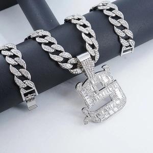 Detail einer Iced-Out Gliederkette mit kristallbesetztem B-Anhänger auf schwarzem Leder