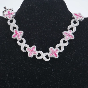 Dettaglio di gemme rosa a forma di quadrifoglio su collana a maglia cubana infinity