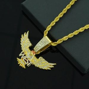 Makroaufnahme: Adler-Anhänger in Gold mit WEST-Schriftzug und Kristallen an Kordelkette