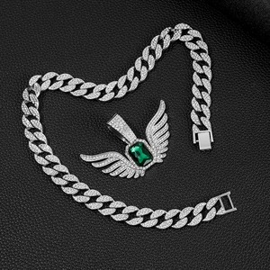 Detail van engelenvleugel hanger met groene smaragd op een iced-out Cuban schakelketting