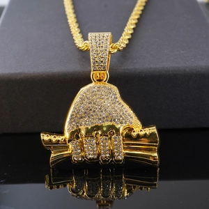 Gros plan du pendentif hip hop en or en forme de main tenant de l'argent et cristaux brillants