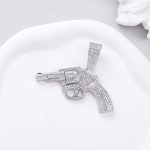 Detalle del colgante de revólver hip hop plateado con incrustaciones de cristales blancos