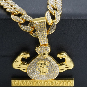 Macro shot of gold money power pendant with iced-out dollar sign and muscles on Cuban chain