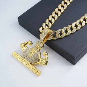 Detailed close-up of iced-out gold money bag pendant with muscular arm on Cuban link chain