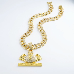 Detailed macro view of iced-out gold money bag pendant with muscular arm on Cuban link chain