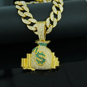 Macro detail of gold hip hop money bag pendant with green rhinestones and cuban chain