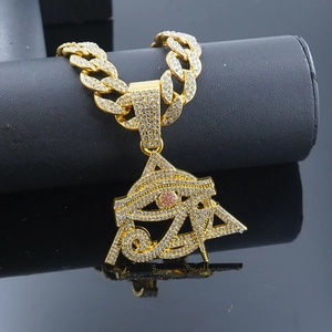 Macro side view of Eye of Horus hip hop pendant with pink crystals and gold Cuban chain