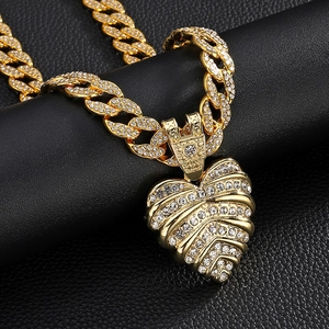 Dettaglio della collana con ciondolo a cuore dorato con strass su catena a maglia cubana