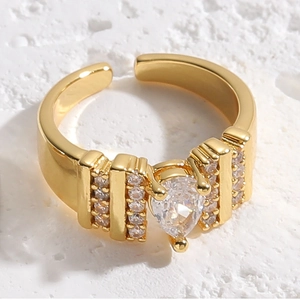 Detailed macro shot of a gold teardrop zircon adjustable ring on a white stone background