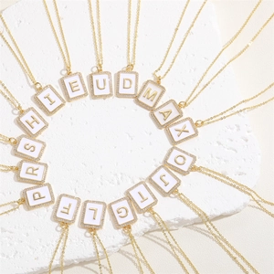 Detailed macro of rectangular white enamel alphabet pendants with cubic zirconia and gold chain