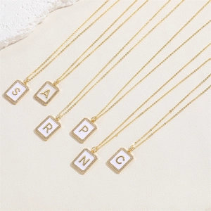 Macro detail of gold initial necklaces with zircon inlay and rectangular pendants