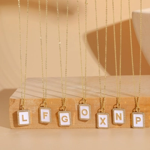 Gold zircon initial necklace with white enamel pendants featuring letters L, F, G, O, X, N, P