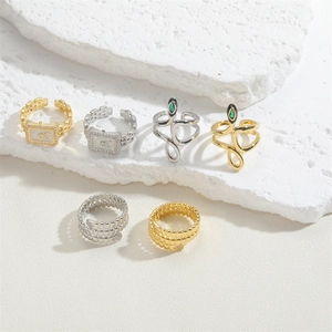 Detailed set of snake-shaped and watch-style rings with zircon inlay on stone surface