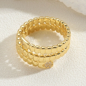 Macro shot of gold snake-shaped multi-layer ring with sparkling white zircon stones