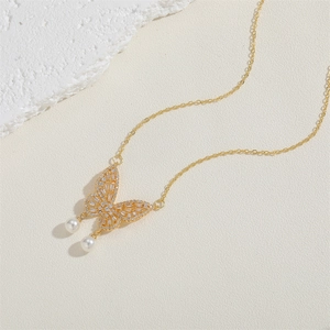 Détail du pendentif papillon doré serti de zircons avec d'élégantes perles blanches