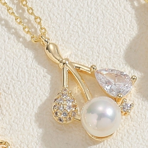 Vue macro du pendentif cerise en or avec perle, zircon en goutte et détails scintillants