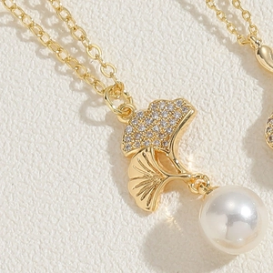 Détail macro du pendentif feuille de ginkgo avec zircons et perle blanche
