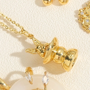 Macro shot of gold-plated jewelry set featuring rabbit pendant and white gemstones