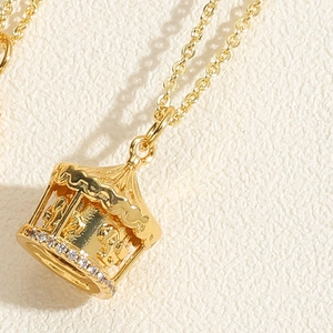 Close-up of golden carousel pendant with white zircon inlay on white textured background
