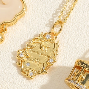 Macro view of vintage gold oval pendant with floral engraving and Love You Wildly text