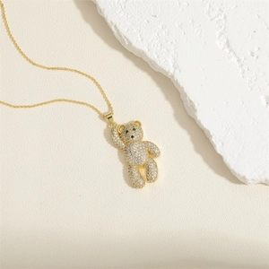 Macro shot of a gold necklace featuring a luxury teddy bear pendant encrusted with white zircons