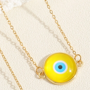 Nahaufnahme einer goldenen Halskette mit rundem, gelbem Evil-Eye-Harzanhänger-Design