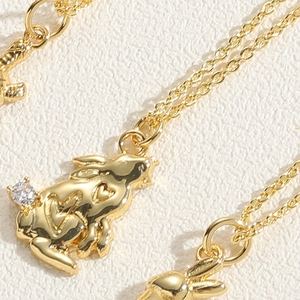Macro shot of gold rabbit pendant with heart cut-outs and zircon stone on fine chain