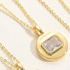 Macro view of gold necklaces with square cut cubic zirconia in round metal pendants