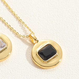 Close-up of dual circular pendants with black and white zircon gemstones on gold chain