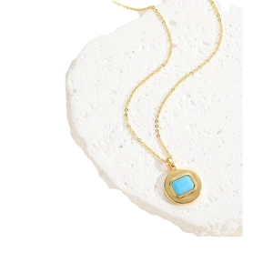 Minimalist gold necklace with a square blue zircon pendant on a natural stone base