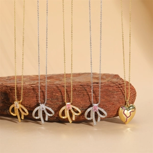 Elegantes 14K vergoldetes Halsketten-Set mit Schleifen- und Herzanhängern auf Holzständer