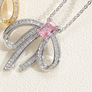 Makroaufnahme der silbernen Schleife mit rosa Edelstein und Kristallen an einer Kette