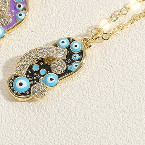 Dettaglio macro della collana con ciondolo a ciabatta malocchio con zirconi e smalto